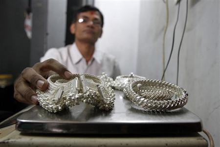 A silver trader weighs his silver ornaments inside his shop in the western Indian city of Ahmedabad